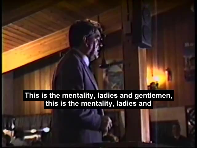 Irving speaking at a lectern in Milton, Ontario, 1991, with burned captions across the frame.